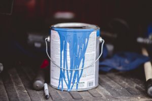 A selective focus shot of bucket of blue paint on a metal surface in an attic