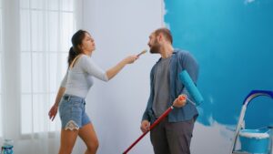 NJ Paints team demonstrating regular interior painting technique as young couple paints wall in New Jersey home